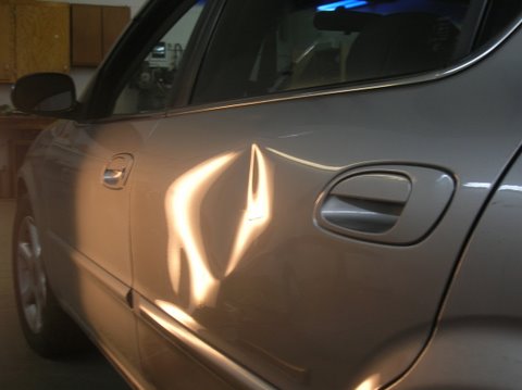 Maxima Door with large dent before paintless repair